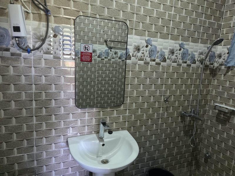 Bathroom with a pedestal basin, mirror and wall-mounted water heater